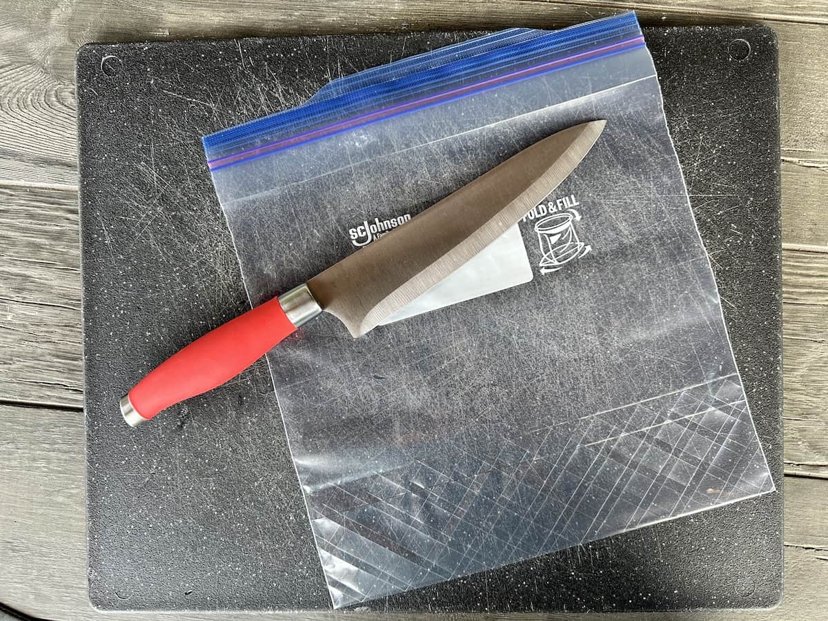 black cutting board zip top bag chefs knife with red handle