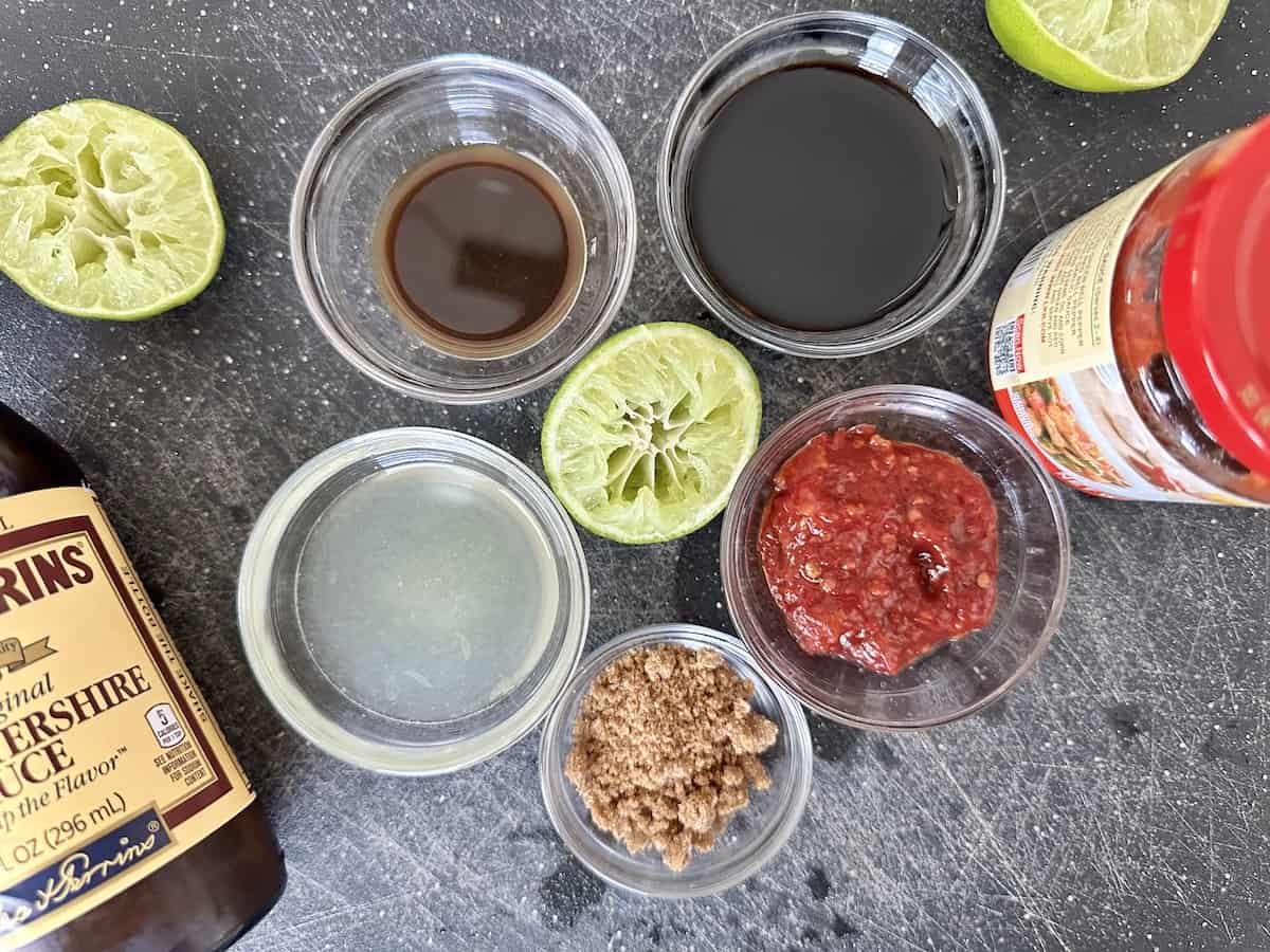 glass bowls of Worcestershire sauce soy sauce garlic chili paste lime juice brown sugar lime cut in half bottled marinade ingredients