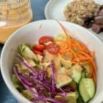 bowl of salad with ginger salad dressing mason jar of more dressing and plate of hibachi steak