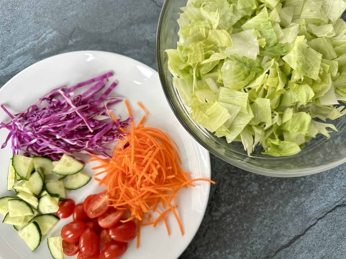 chopped iceberg lettuce shredded carrots red cabbage cucumber and tomato