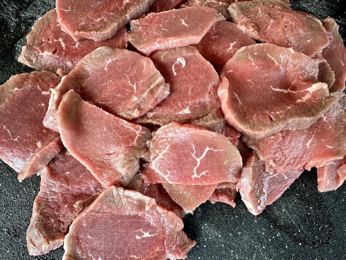 thinly sliced top round beef on black cutting board