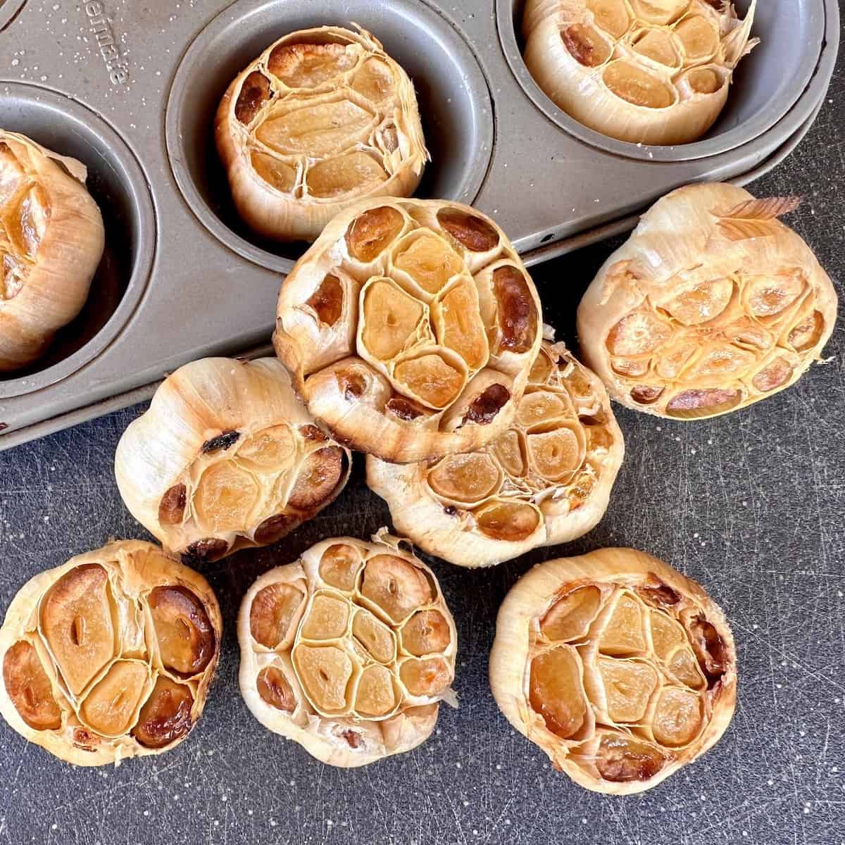 smoked heads of garlic on black cutting board