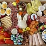easter charcuterie board with cheeses meats vegetables fruit and spreads