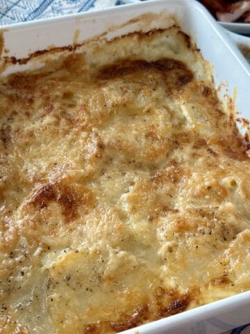 au gratin potatoes with golden brown crust in white baking dish on kitchen table