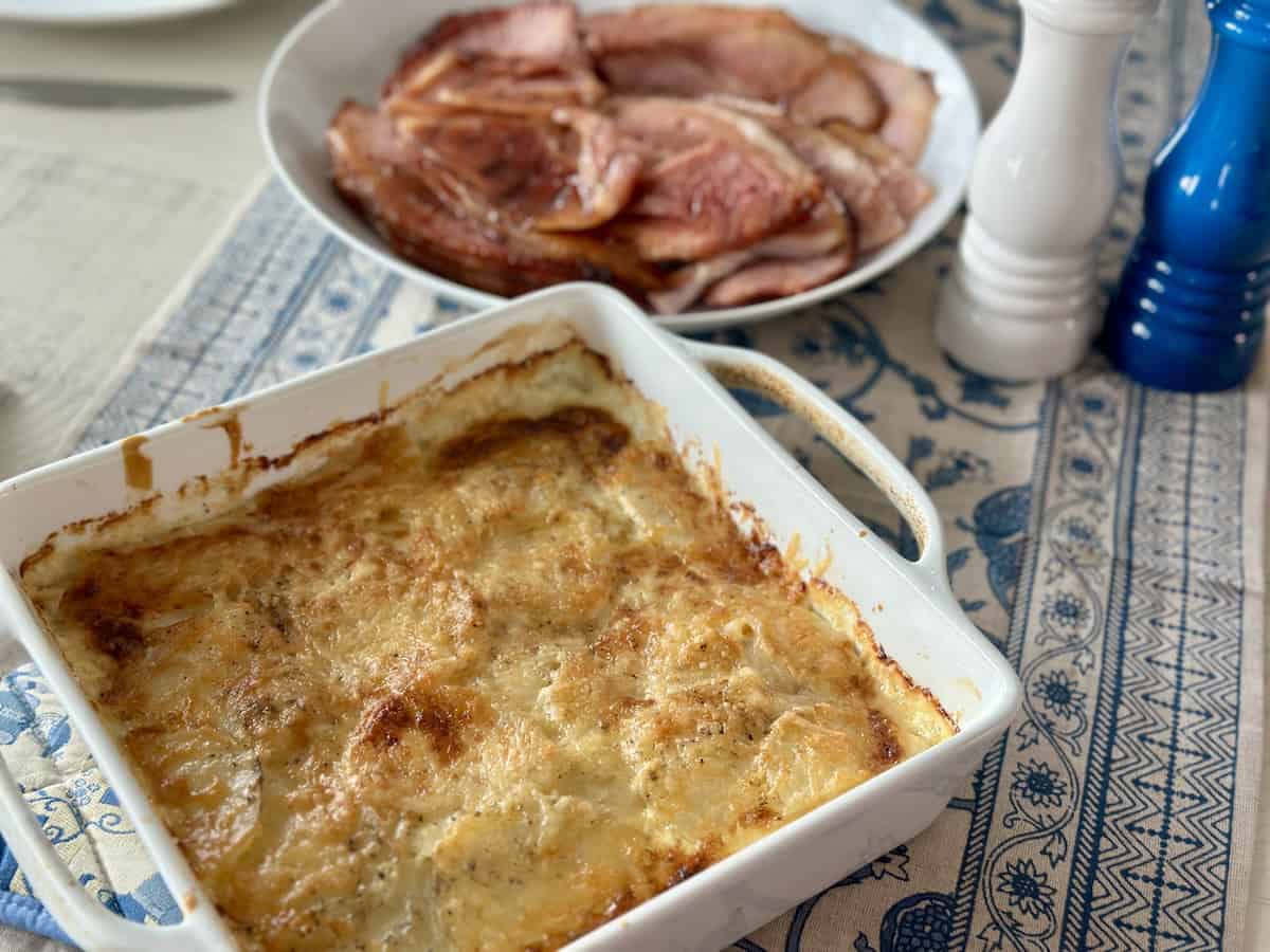 A casserole dish with au gratin potatoes and ham on a table