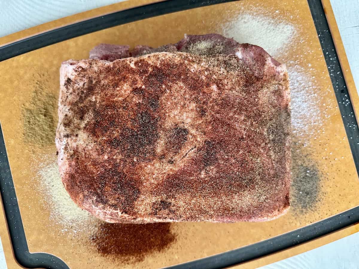 pork shoulder seasoned with spices on wood cutting board