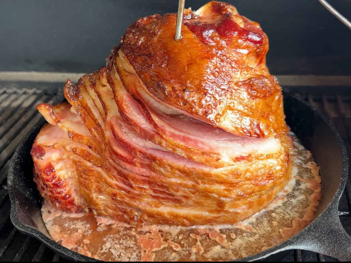 spiral ham cooking in cast iron pan with meat thermometer