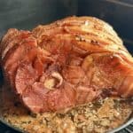 traeger smoked spiral ham in cast iron pan with juices set on a traeger grill