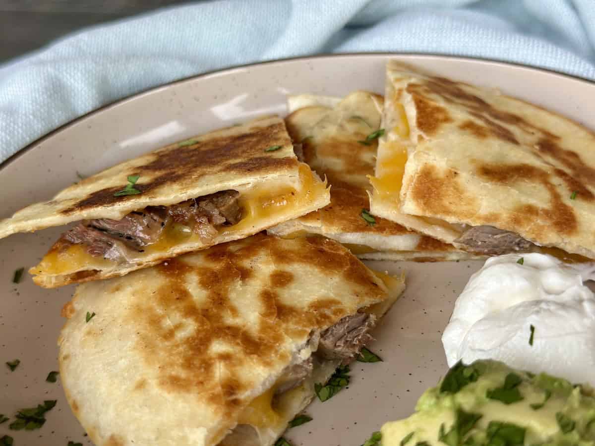 carne asada quesadilla on plate sour cream and guacamole