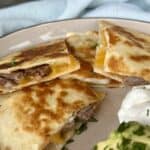 carne asada quesadilla on plate sour cream and guacamole