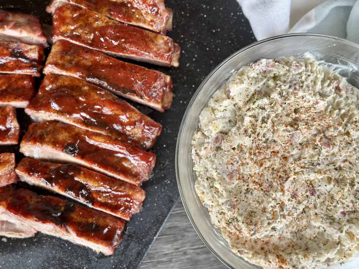 Ribs and potato salad without eggs on a cutting board