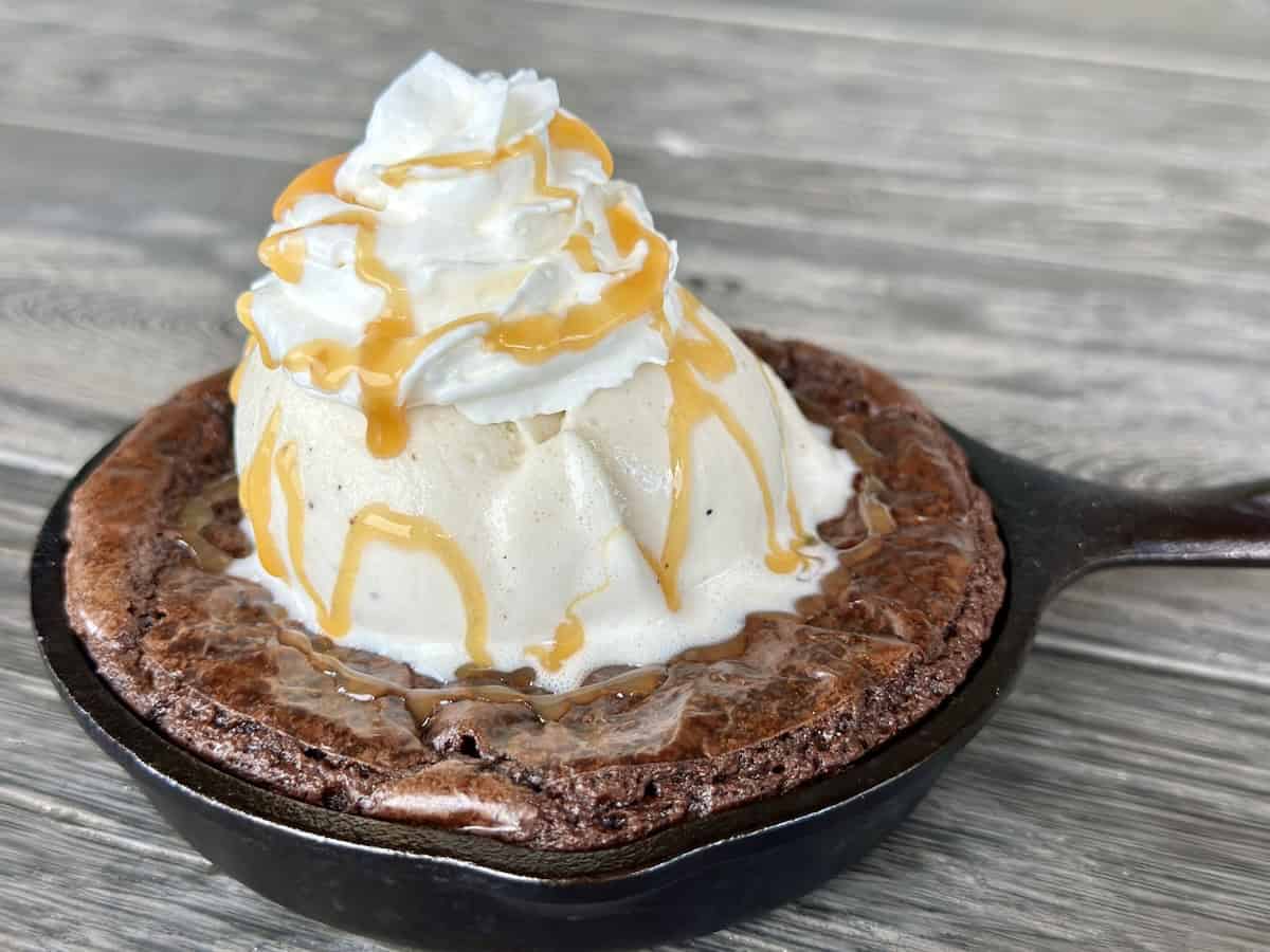 skillet brownie with vanilla ice cream whipped cream wood table