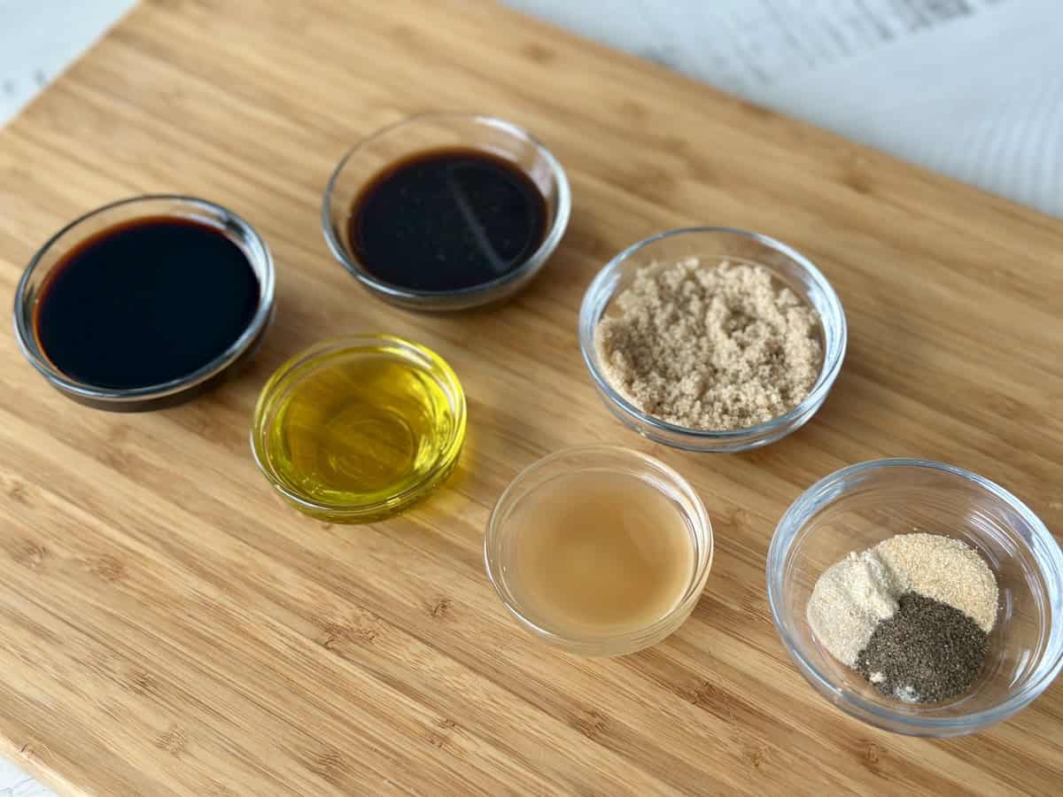 meat marinade ingredients in glass bowls on wood cutting