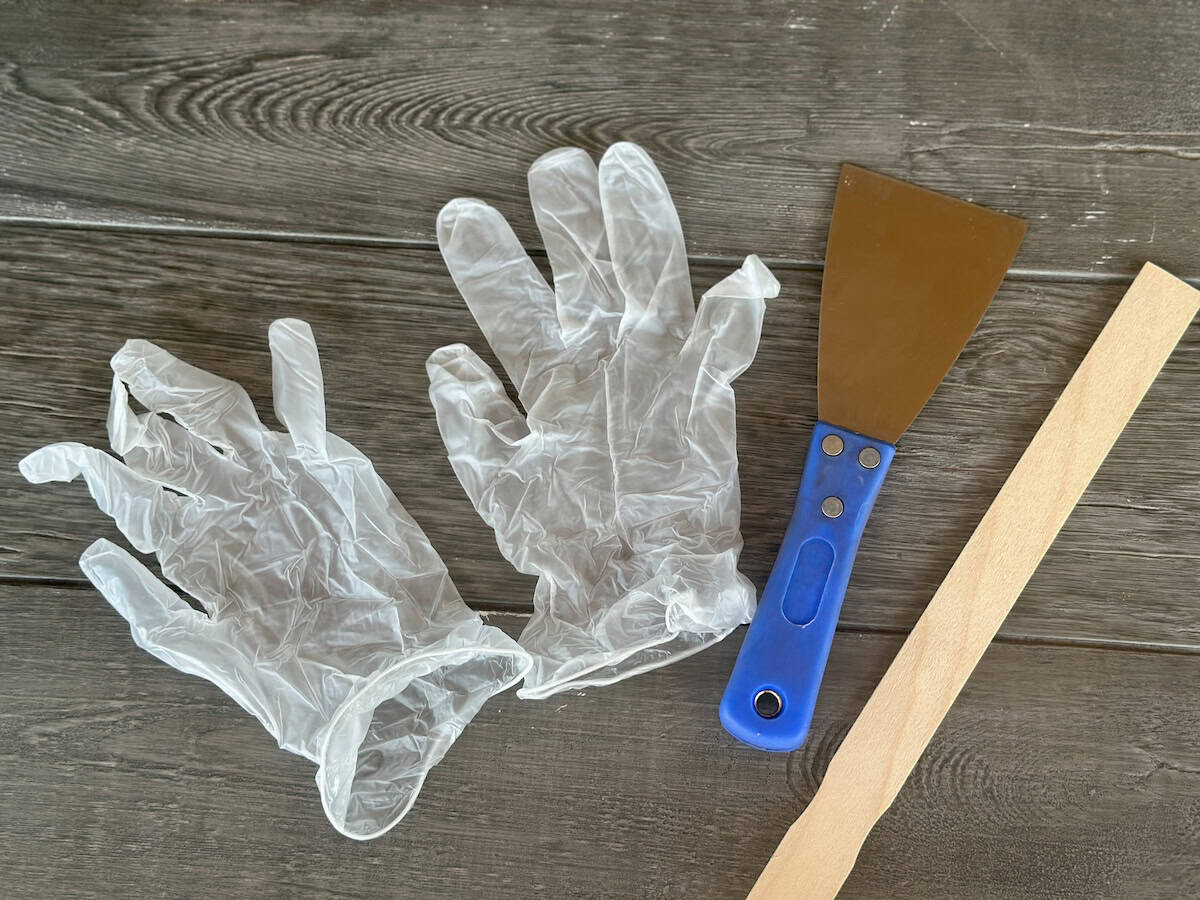 plastic gloves putty knife and wood stir stick for paint