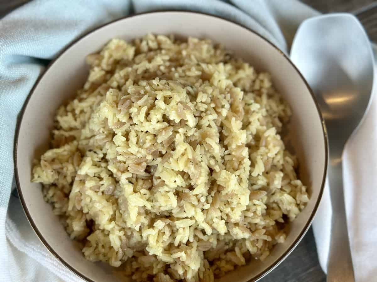 rice pilaf in brown bowl green kitchen towel