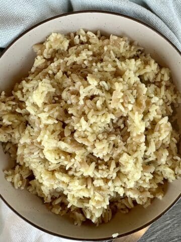 rice pilaf in brown bowl green kitchen towel