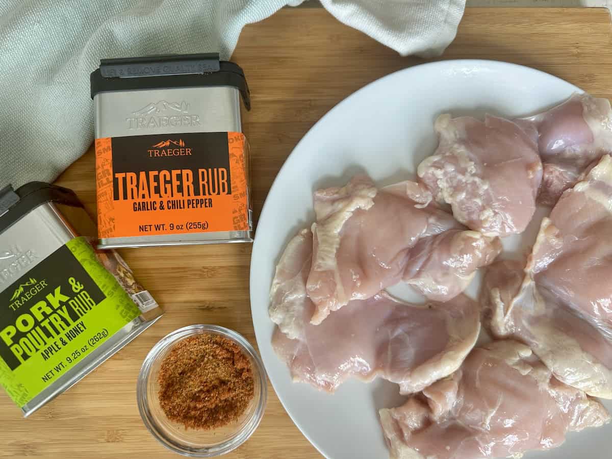traeger rub traeger pork and poultry rub white plate of raw chicken thighs on wood cutting board