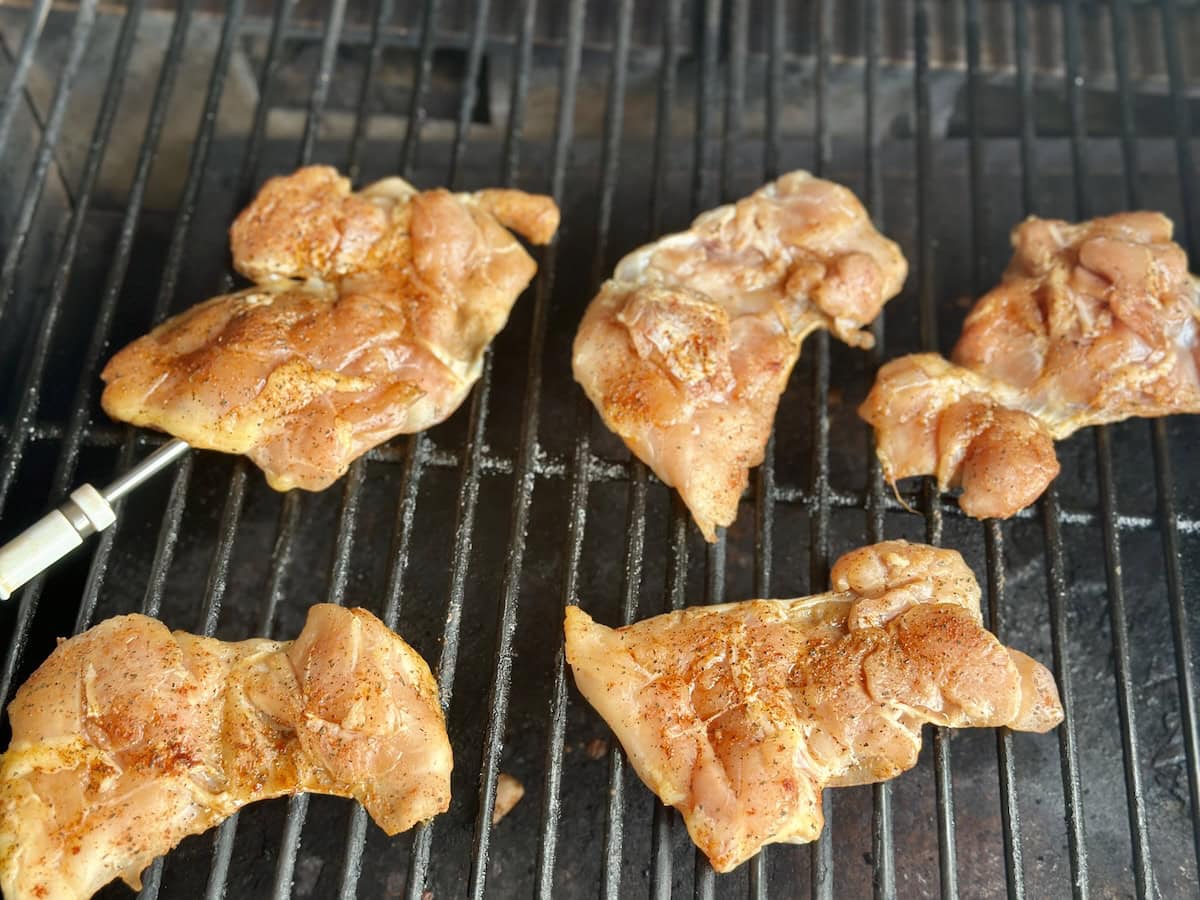 chicken thighs cooking on grill grates