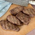 5 tri tip steaks on wood cutting board with knife