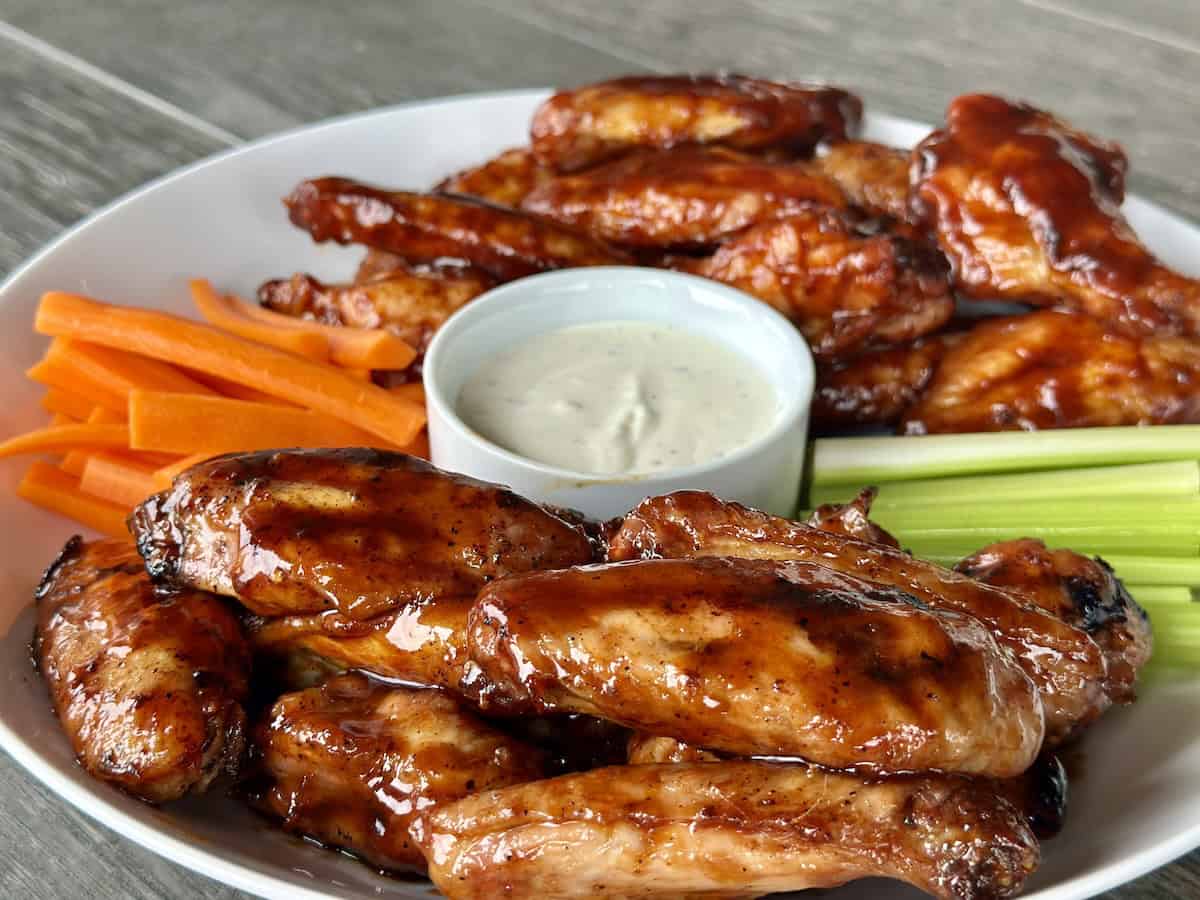 chicken wings on white plate with carrots and celery