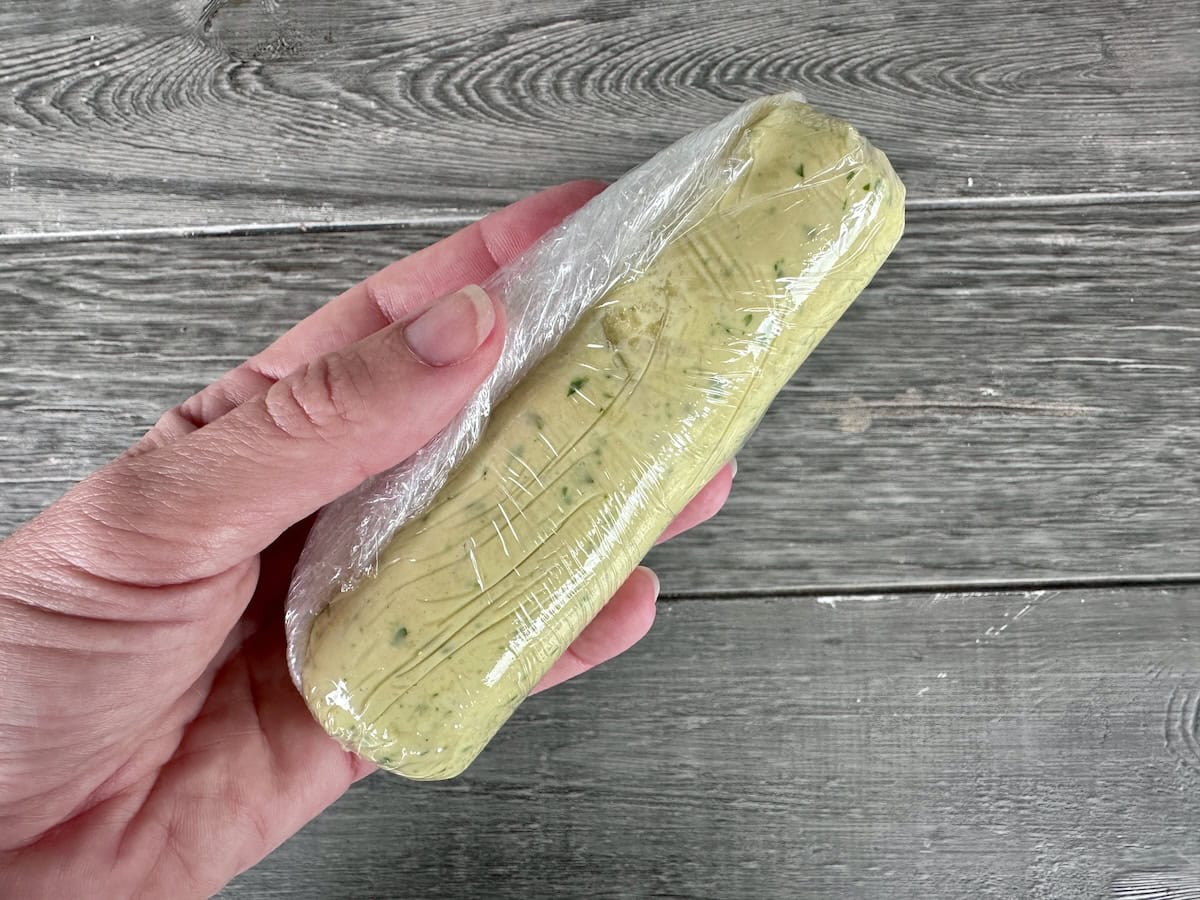 hand holding garlic butter tube in plastic wrap