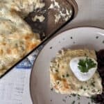Sour cream enchilada casserole on tan plate enchilada casserole in glass baking dish