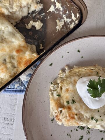 Sour cream enchilada casserole on tan plate enchilada casserole in glass baking dish