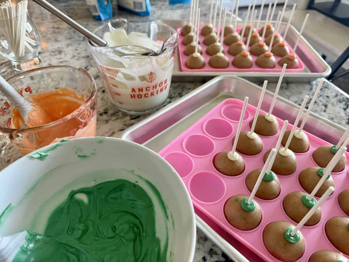 cake pop balls with lollipop sticks melted chocolate in glass measuring cups