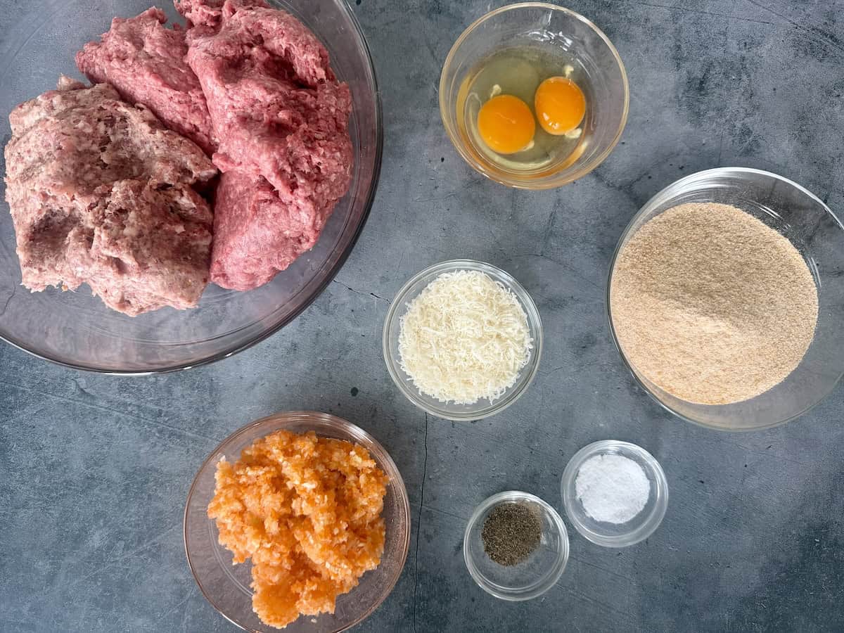 meatball ingredients measured in glass bowls on blue background