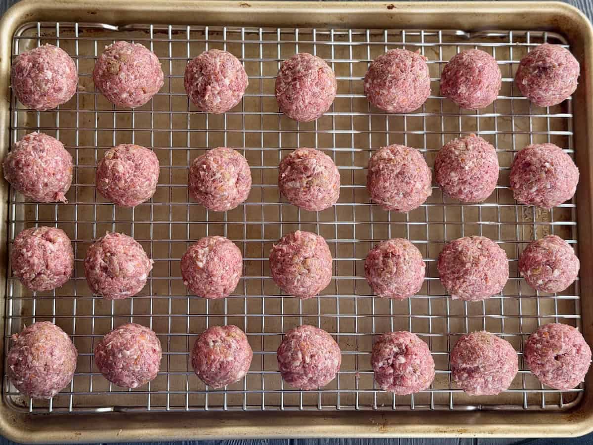 uncooked meatballs on sheet pan with wire rack