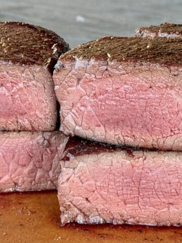 two filet mignon steaks cut in half on cutting board