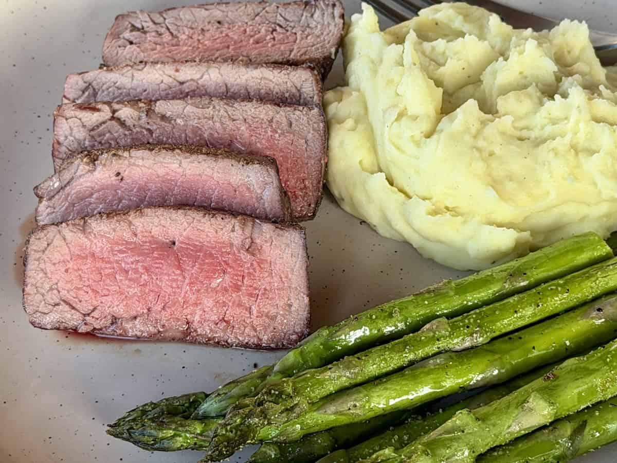 sliced filets cooked with a warm red center and pink through mashed potatoes and asparagus