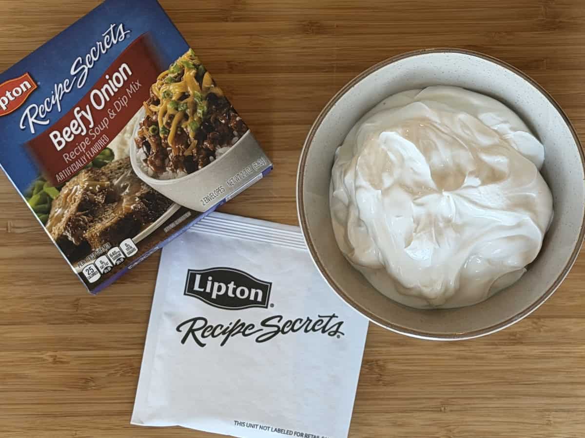 boxed beefy onion soup mix bowl of sour cream wood cutting board