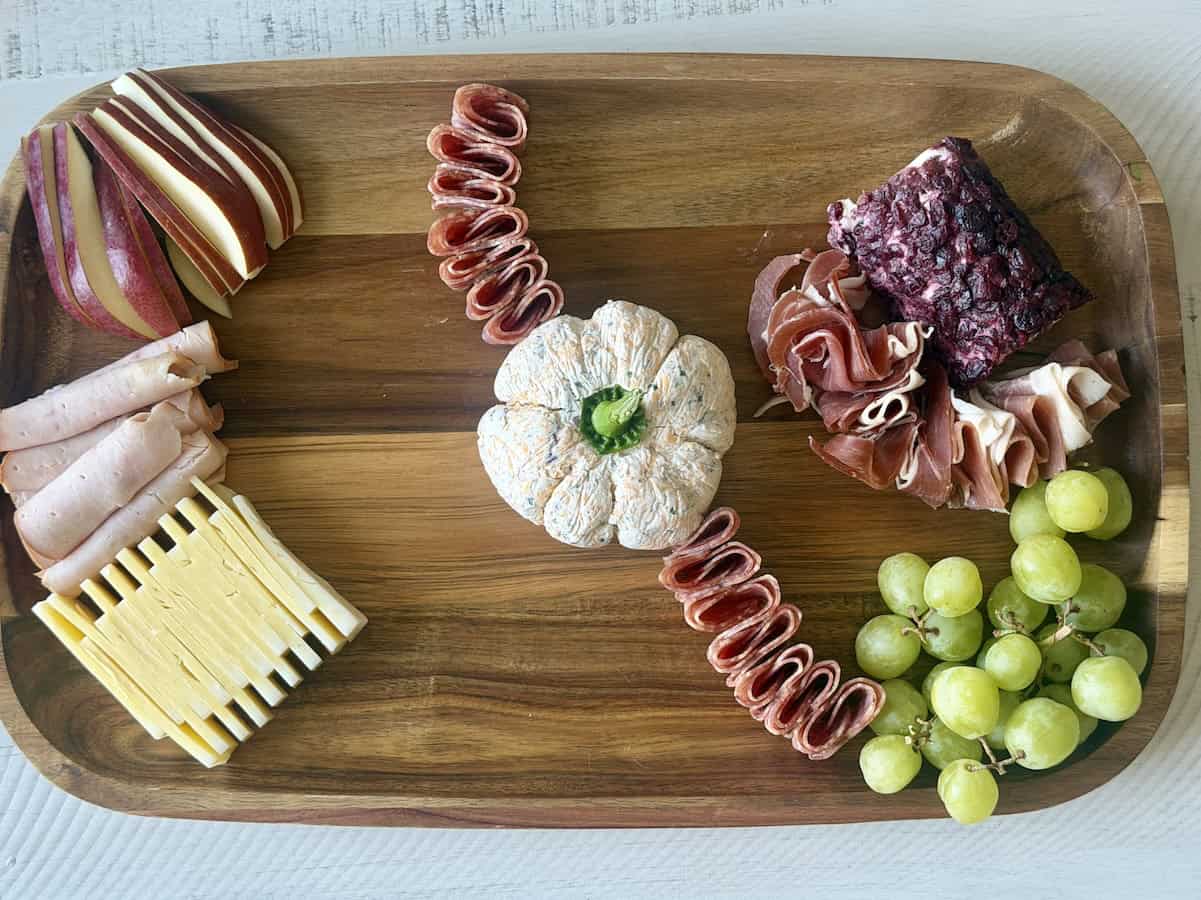 wood board cheese pumpkin meats sliced cheese green grapes and pears