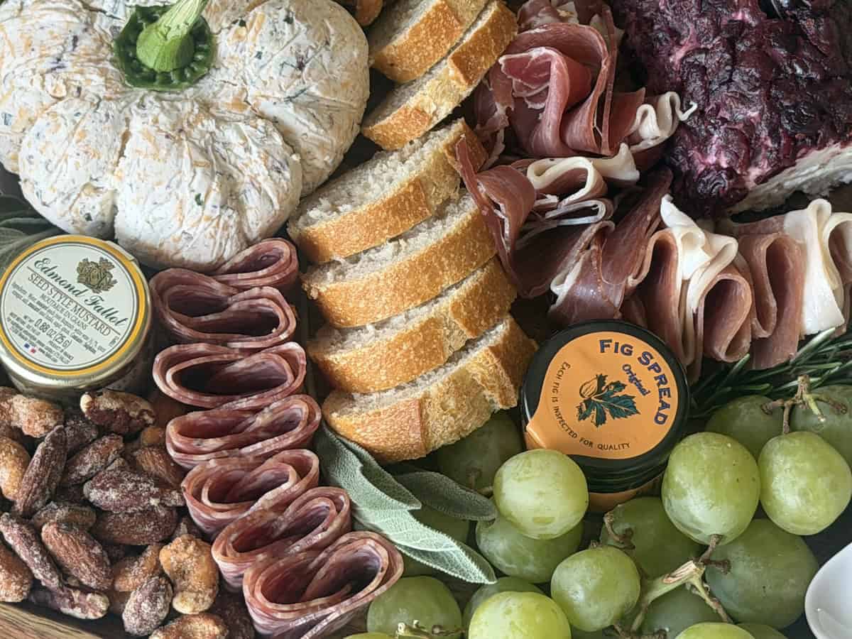 thanksgiving themed charcuterie board with salami sliced baguette fig spread grapes