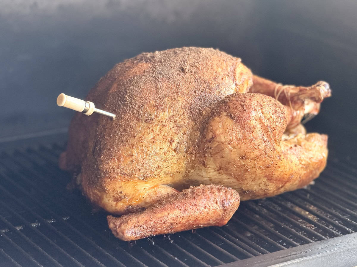 Roast whole chicken on grill with seasoning and crispy skin for delicious outdoor cooking on traeger grill