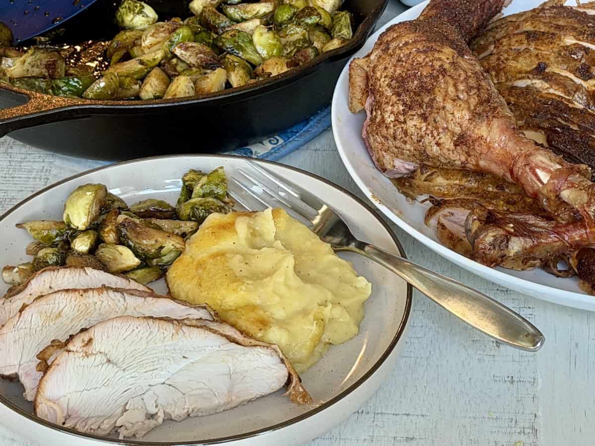 smoked turkey on a plat with mashed potatoes and brussel sprouts
