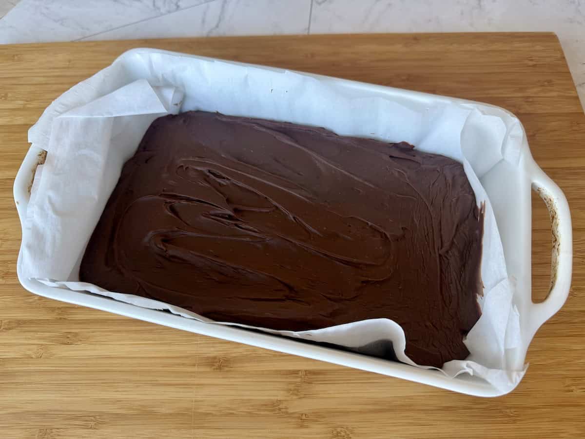 jack Daniels whiskey fudge in white baking dish lined with parchment on wood cutting board
