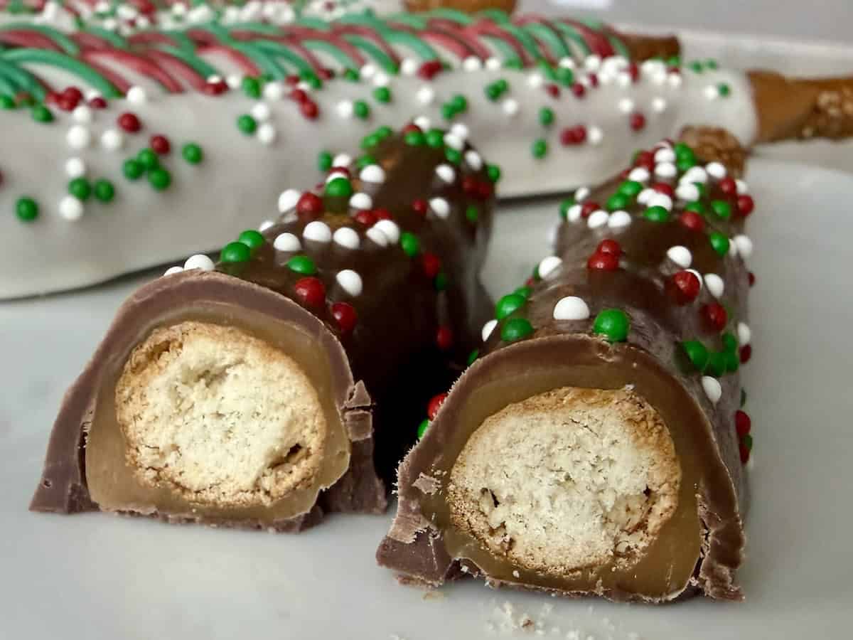chocolate and caramel dipped pretzel cut in half on white plate