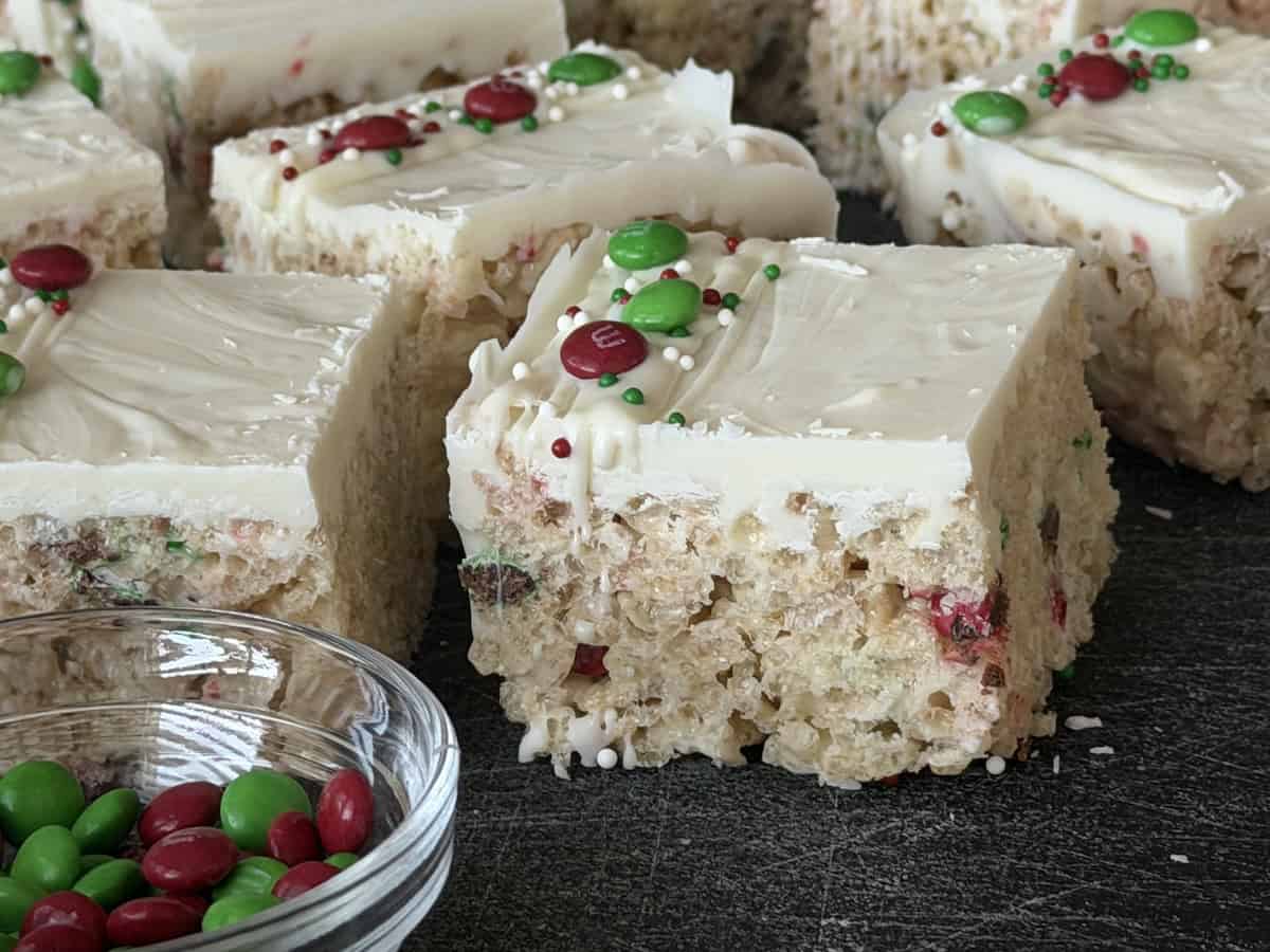 christmas Rice Krispie treats on black cutting board bowl of mini m&ms
