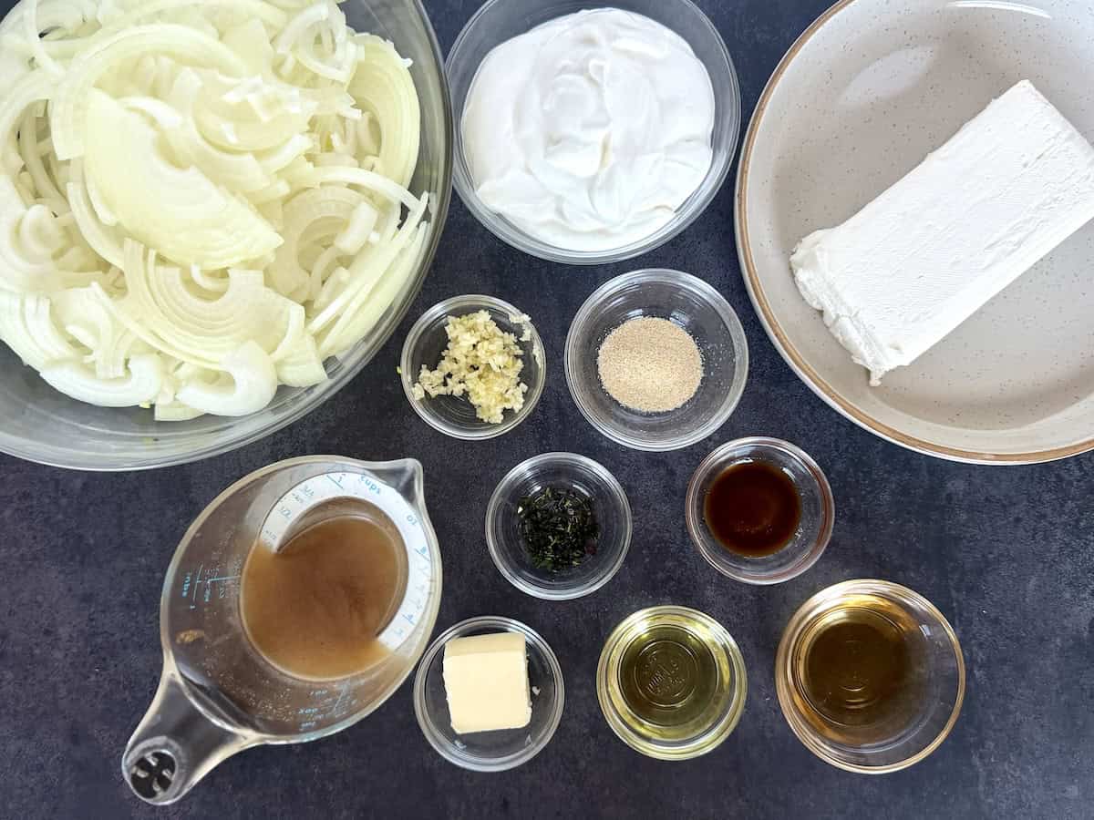French onion dip ingredients in glass bowls sliced onions cream cheese sour cream herbs and beef stock