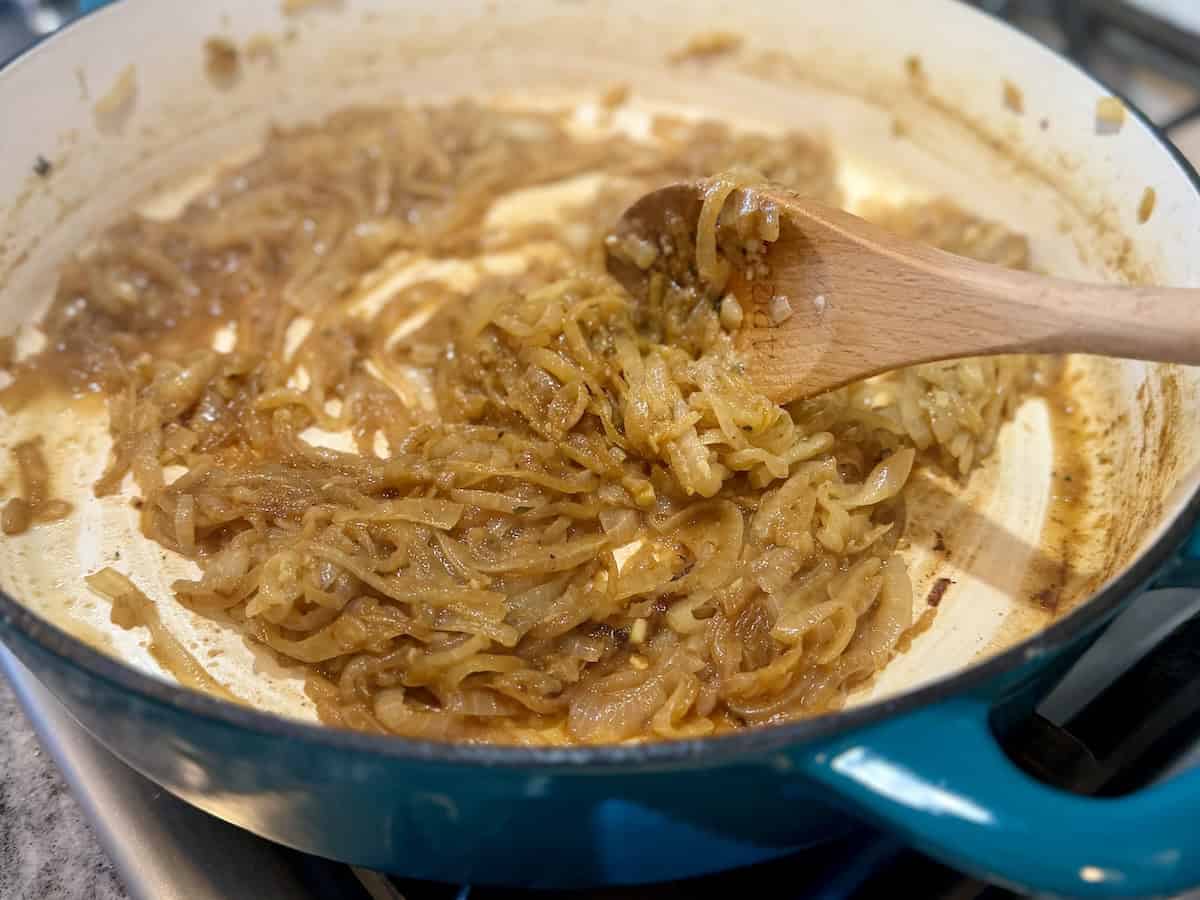 caramelized onion in teal pan wooden spoon