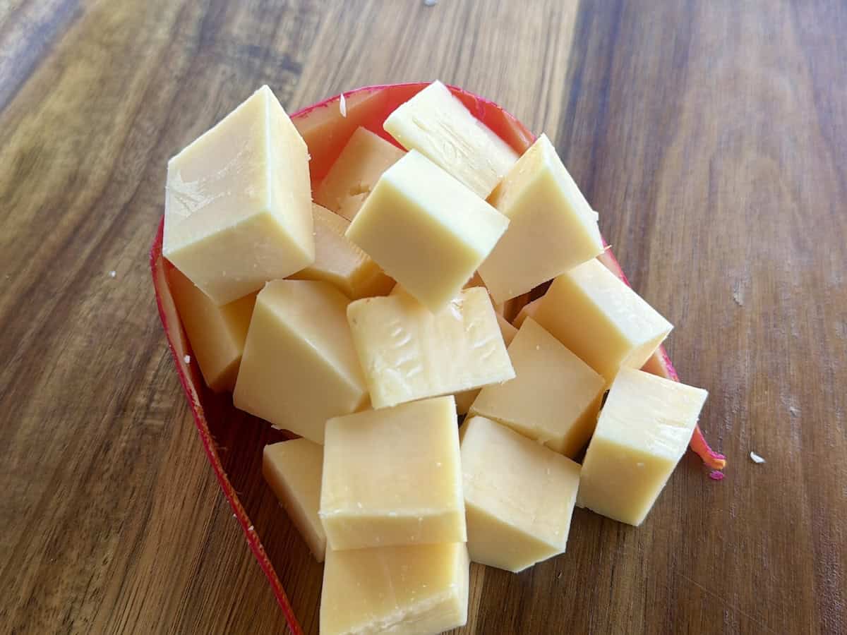 gouda cheese cut in cubes with red rind wrapped around it