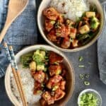 two bowls bourbon chicken with rive stir fried vegetables chopsticks blue napkins