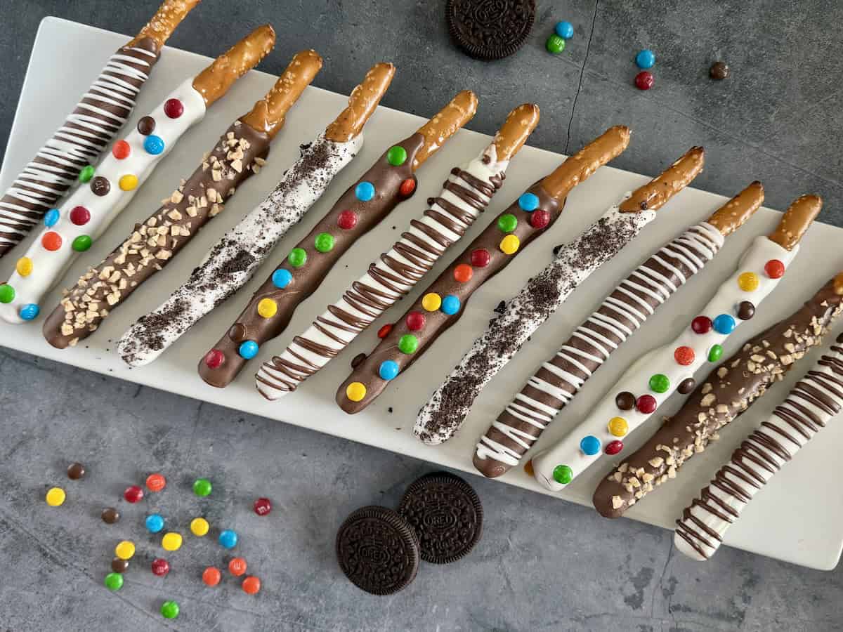 caramel and chocolate dipped pretzel rods variety of toppings white platter