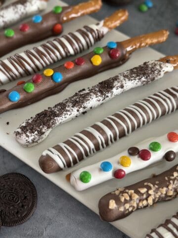 caramel and chocolate dipped pretzel rods variety of toppings white platter