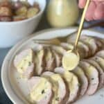 pork tenderloin with mustard sauce gold spoon serving sauce white plate