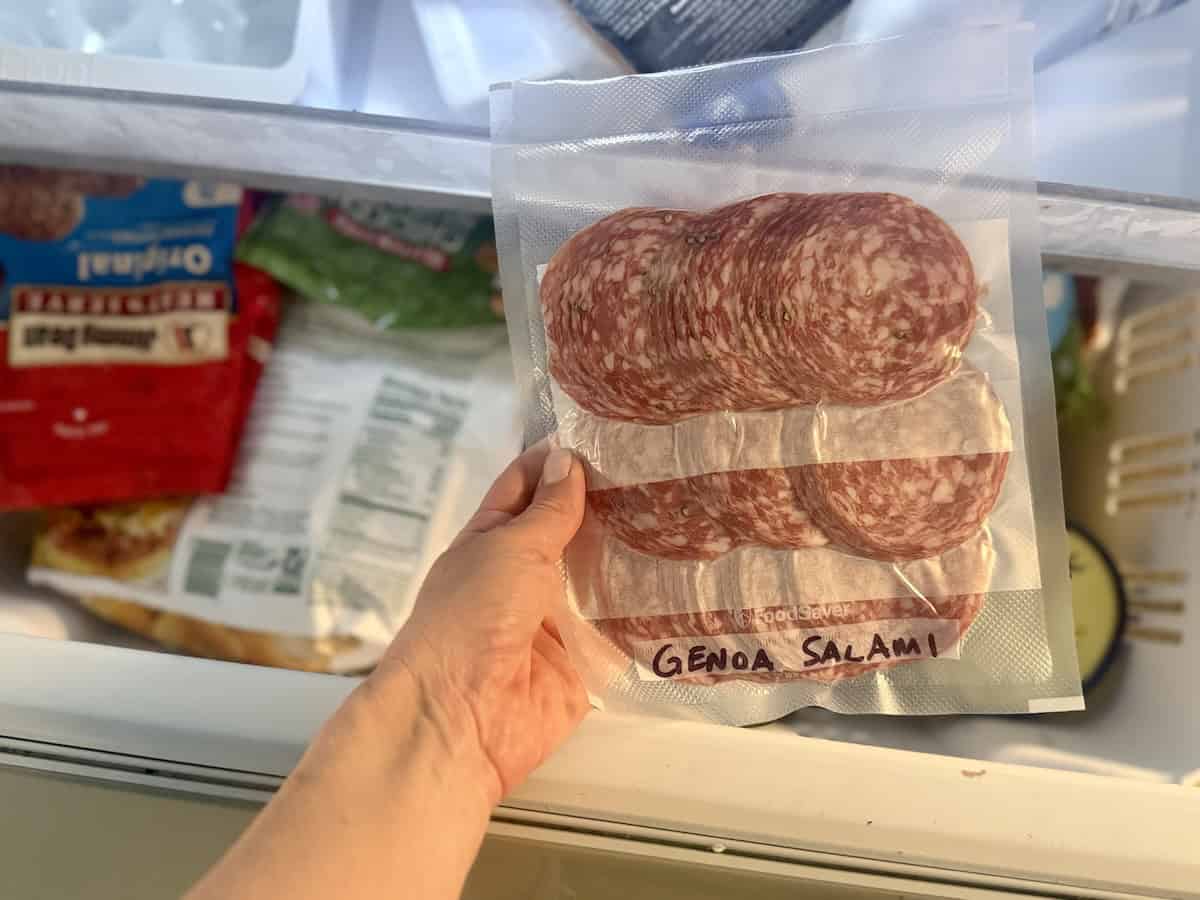 vacuum sealed package of salami being taken out of freezer