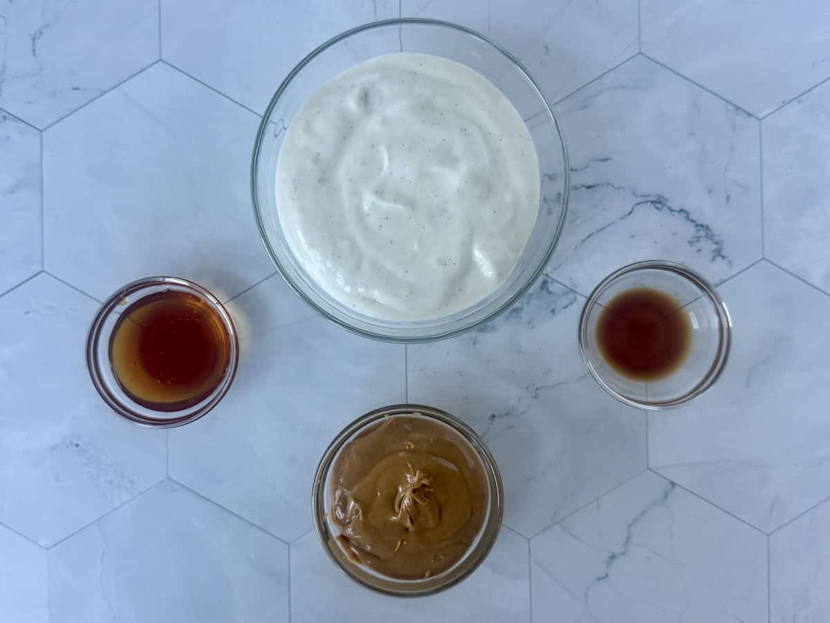 meaured peanut butter dip ingredients in glass bowls on marble counter