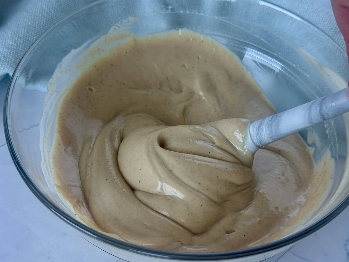 spatula stirring peanut dip in glass bowl